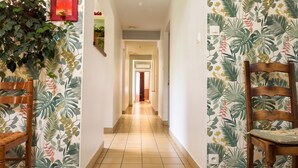 A hallway with a wooden chair, a mirror, and a light switch on the wall.