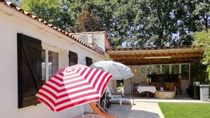 A patio with outdoor seating, a covered area, and a white building with shutters.