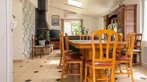 A dining area with a wooden table and chairs, a television, and a potted plant.
