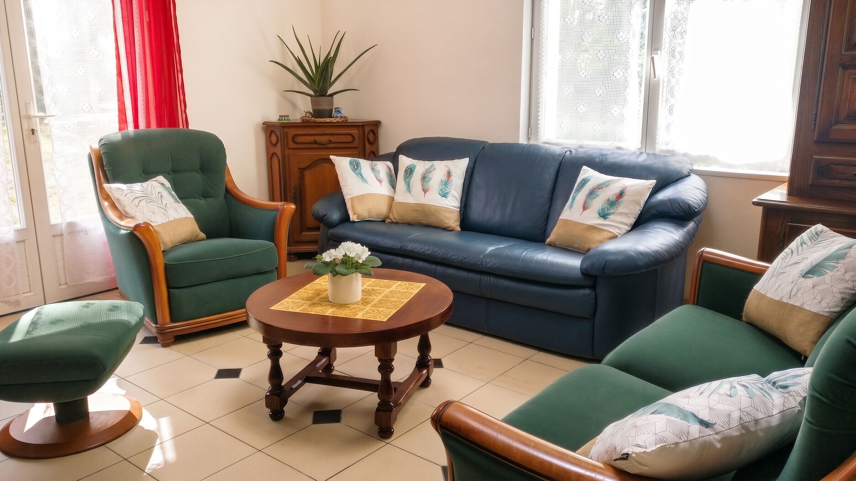 Un salon avec un canapé bleu, des fauteuils verts et une table basse en bois.