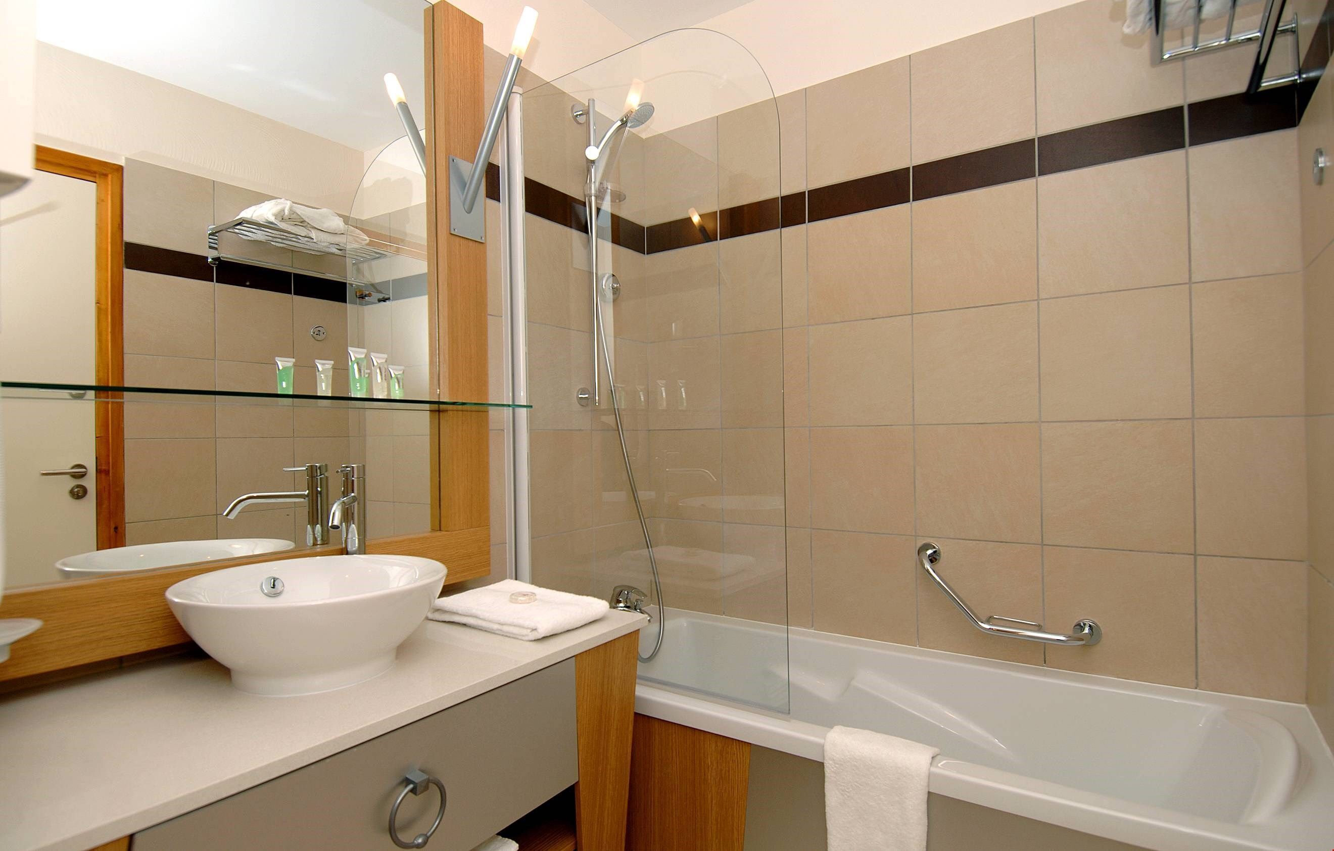 A modern bathroom with a glass-enclosed shower, a white bathtub, and a large mirror above a white sink.