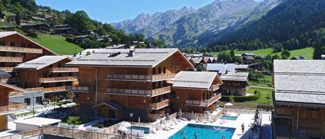 A wooden chalet-style hotel with a pool and mountain views.