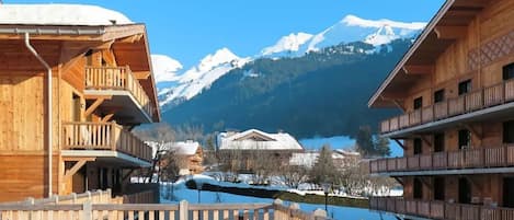 A wooden chalet with balconies overlooking a snowy mountain landscape.