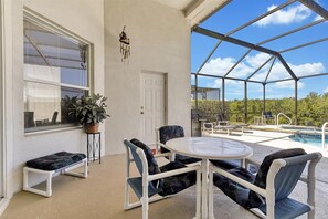 A covered patio with a pool, outdoor seating, and a view of the surrounding landscape.