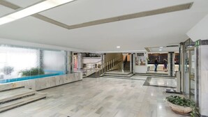 A spacious lobby with a marble floor, a water feature, and a staircase leading to upper levels. - Cozy apartment with pool and sea views (Benalmádena)