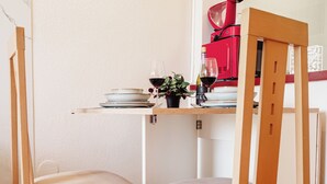 A corner of a room with a wooden chair, a small table, and a red appliance. - Cozy apartment with pool and sea views (Benalmádena)