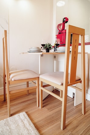 A corner of a room with a wooden chair, a small table, and a red appliance. - Cozy apartment with pool and sea views (Benalmádena)