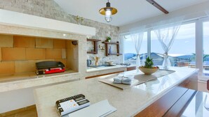 Een moderne keuken met een betegelde achterwand, een ingebouwde grill en een groot raam met uitzicht op zee.