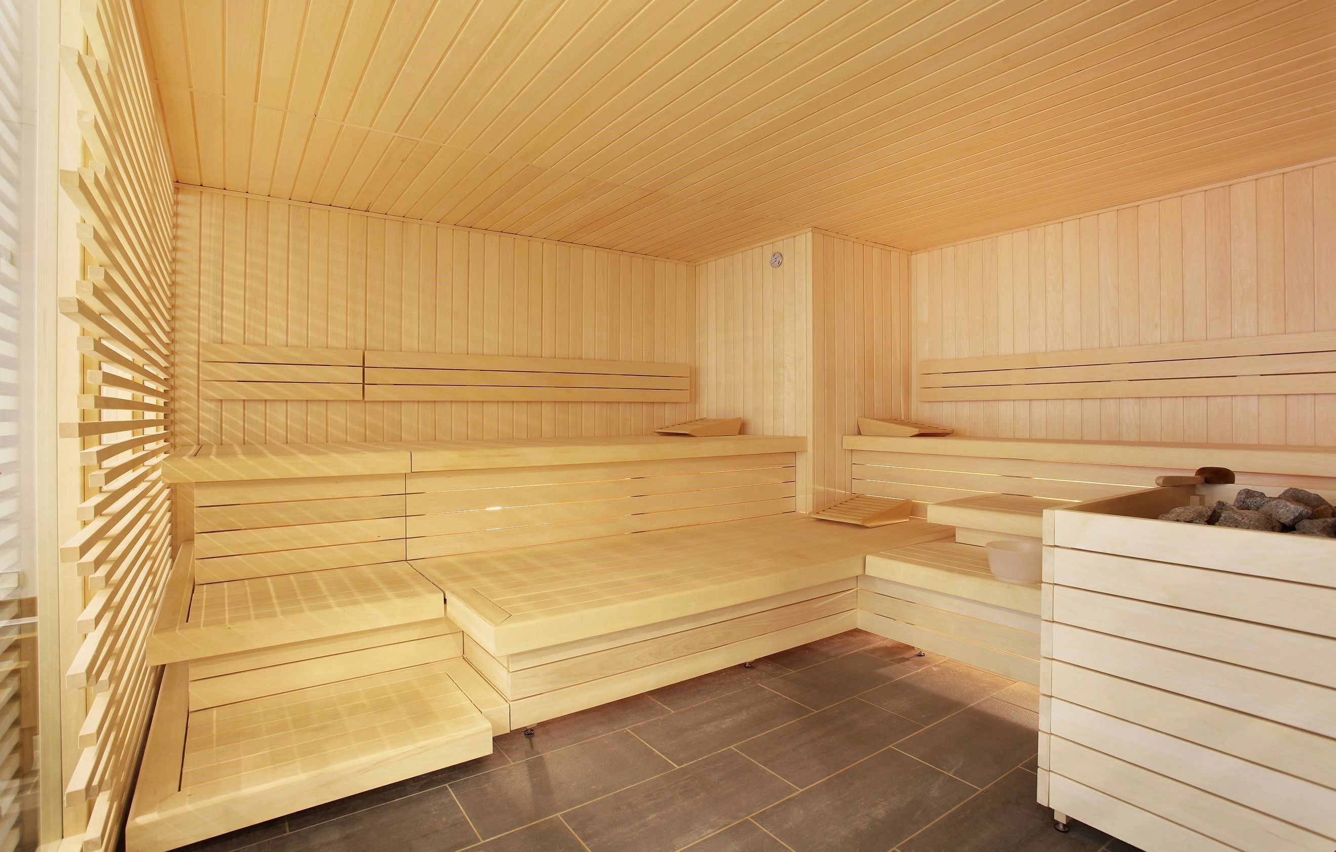 Un sauna avec des bancs en bois et un bassin en pierre.