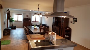 A modern kitchen with a central island, stainless steel range hood, and a dining area with a wooden table and chairs.