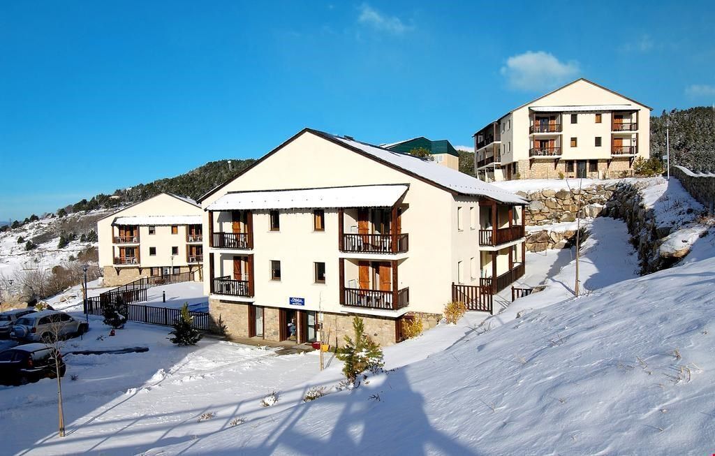 Ein Hotel mit mehreren Balkonen, eine verschneite Landschaft und ein klarer Himmel.