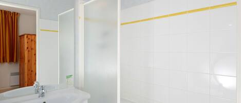 A bathroom with a white sink, mirror, and white tiled walls.
