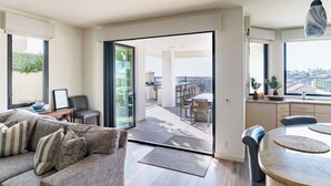 Un salon moderne avec un canapé, une table à manger et une vue sur un balcon extérieur.