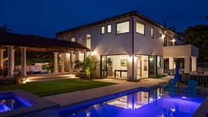 Une maison moderne dotée d’une piscine, d’un espace extérieur aménagé et d’un patio bien éclairé.