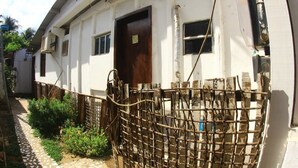 Un bâtiment blanc avec une porte et des fenêtres en bois, une clôture en métal et un chemin pav é.