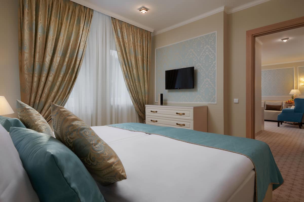 A hotel room with a bed, a TV mounted on the wall, a dresser, and a chair.