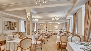 A spacious dining area with multiple tables and chairs, chandeliers, and a mirrored wall. - Honour and Grace Hotel (Ostrov)