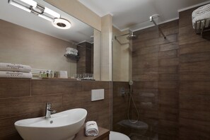 A modern bathroom with a large sink, a glass shower enclosure, and a mirror above the sink. - Honour and Grace Hotel (Ostrov)