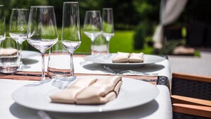 A table set outdoors with clear glasses and folded napkins, suggesting a dining area. - Honour and Grace Hotel (Ostrov)