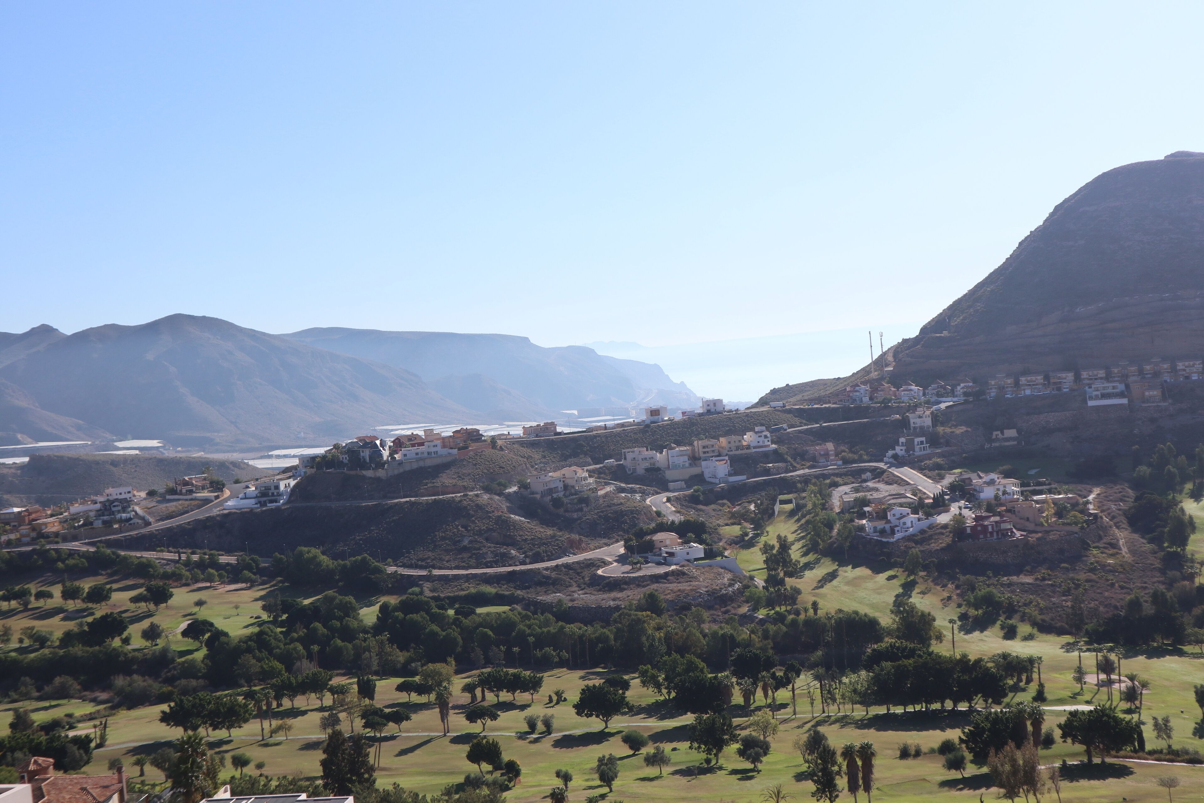 A coastal town with buildings on a hillside, a clear sky, and a view of the sea.