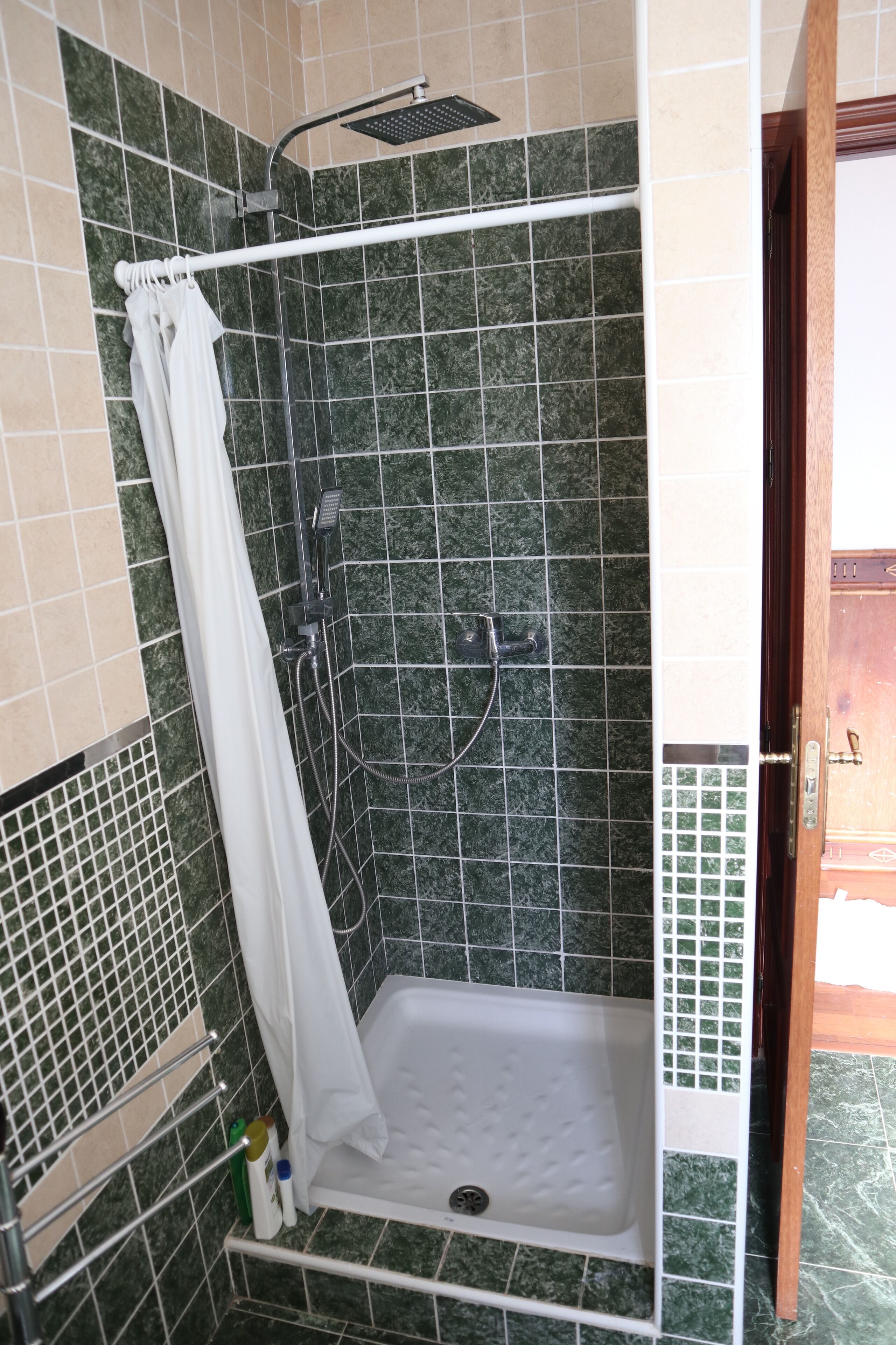 A shower area with a white bathtub, a showerhead, and a curtain.