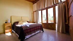 Une chambre à coucher avec un lit, une table de chevet, une fenêtre avec des rideaux et une vue sur l’extérieur.