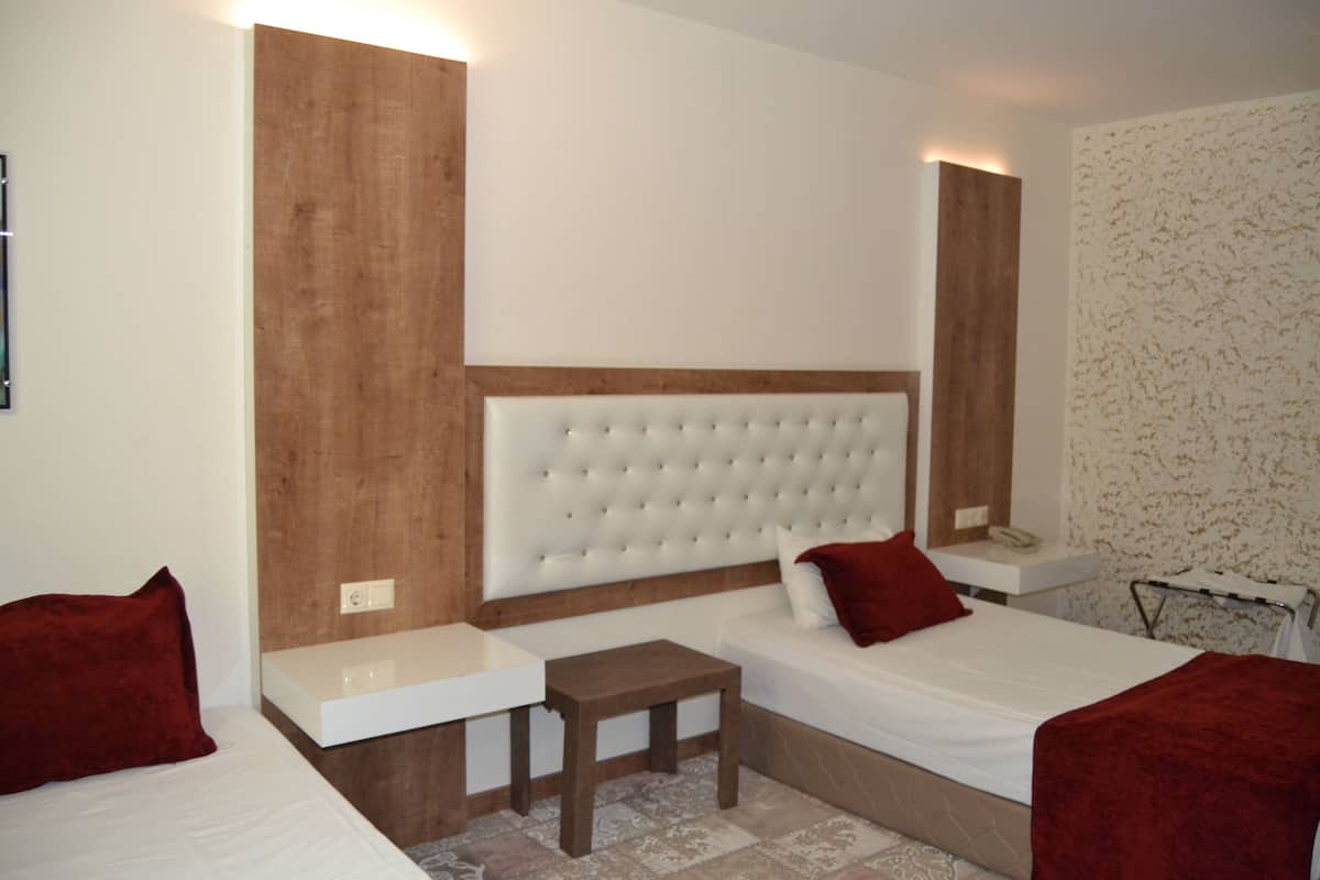 Ein Hotelzimmer mit einem großen Bett, einem kleineren Bett, einem Nachttisch und einem Spiegel.