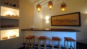 Una zona de bar con tres taburetes, estantes con aperitivos y una obra de arte enmarcada en la pared.