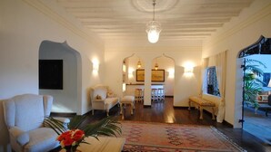 Amplia sala de estar con techo alto, piso de madera y alfombra grande. Hay dos sofás y una mesa de centro con un jarrón de flores.