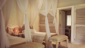 Un dormitorio con cama con dosel, una mesita de noche con lámpara y una silla.
