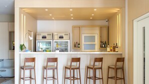 A modern kitchen with a bar area, equipped with stainless steel appliances, bar stools, and a variety of bottles.