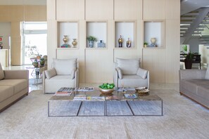 A modern living room with two sofas, a coffee table with magazines, and decorative shelves with vases. - Vie Hotel (Sinop)