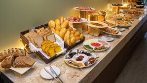 A buffet with various food items including bread, pastries, and meats.