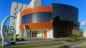 A modern building with a curved glass facade, a wooden section, and a large circular sign with the letters "NICE".