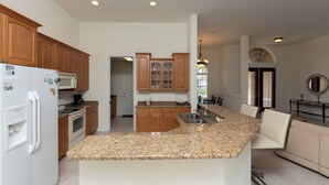 A modern kitchen with granite countertops, wooden cabinets, and a built-in island with a sink.