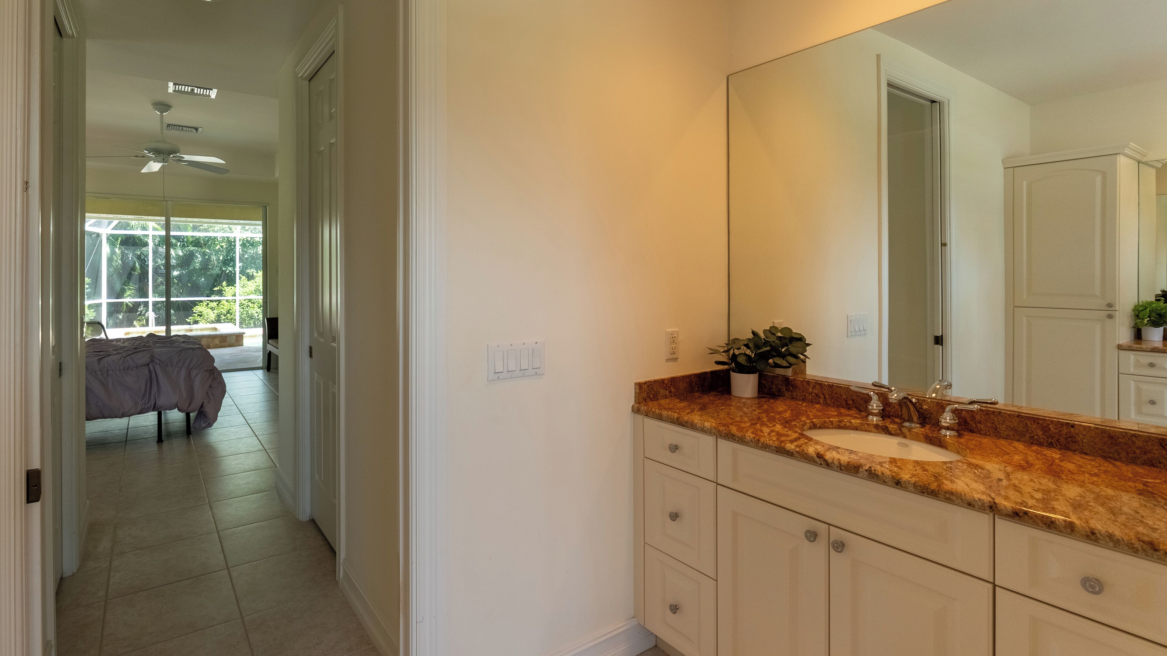 A bathroom with a granite countertop, a large mirror, and a sink.