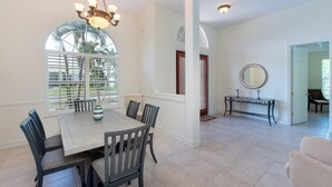 A dining area with a white table, six chairs, a vase, and a chandelier.