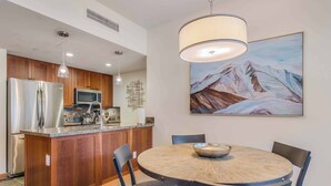 A modern kitchen with wooden cabinets, stainless steel appliances, and a dining area with a round table and chairs. - Capitol Peak Lodge 3417 (Snowmass Village)