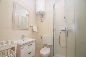 A bathroom with a sink, mirror, toilet, and shower. - Apartments Natasa (Starigrad)