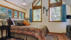 Un dormitorio con una cama grande, varias ventanas, una lámpara y una radio antigua.
