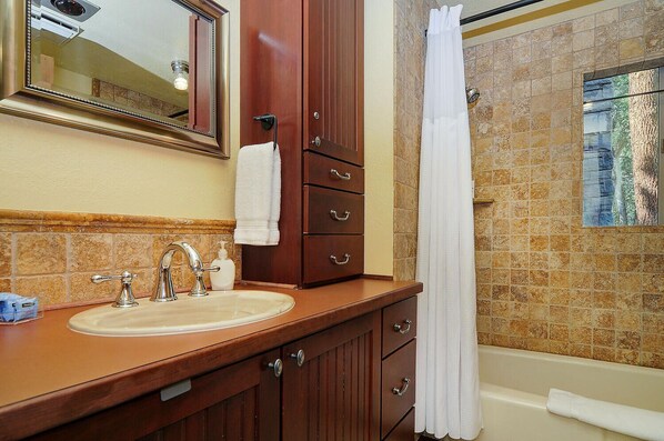 A bathroom with a wooden vanity, a sink, a mirror, a towel rack, and a shower curtain.