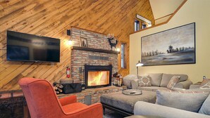 Una sala de estar acogedora con chimenea, un televisor de pantalla plana y un cuadro grande en la pared.