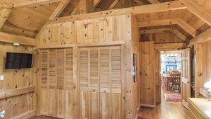 A wooden interior with a large closet, a television mounted on the wall, and a dining area visible through an open door. - Timber frame home only 5 minutes from Windham Mountain - perfect for 2 families! (Windham)