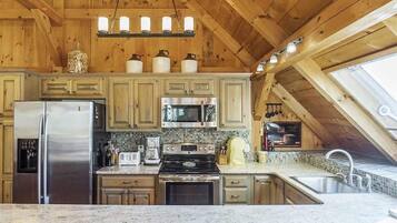 Une cuisine avec des meubles en bois, un réfrigérateur en acier inoxydable, un four à micro-ondes, une cuisinière et un évier.