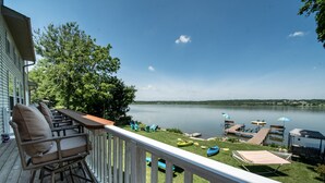 A wooden deck with outdoor furniture and a view of a lake. - Large Lakefront Home on Lake Como - Private Pier! (Lake Geneva)
