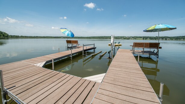 A wooden dock extending into calm water with two benches and umbrellas. - Large Lakefront Home on Lake Como - Private Pier! (Lake Geneva)