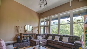 A spacious living room with a large sectional sofa, a coffee table, and a dining area with a small table and chairs. - Canmore center 5BR+4.5BTH Mt view private hot tub (Canmore)