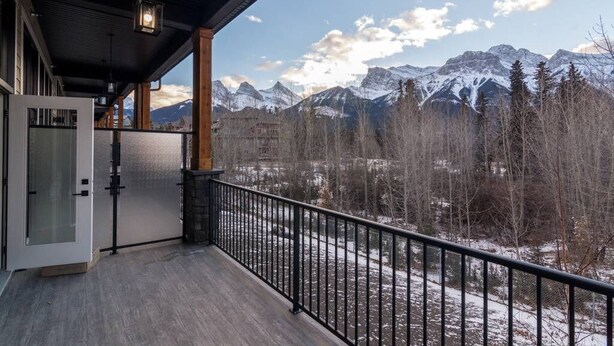 A balcony with a view of snow-capped mountains and a forested valley. - Canmore center 5BR+4.5BTH Mt view private hot tub (Canmore)