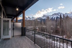 Un balcon offrant une vue sur des montagnes enneigées et une vallée boisée.