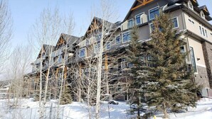 A multi-story hotel with a modern architectural design, featuring a prominent triangular roof structure and multiple windows. - Canmore center 5BR+4.5BTH Mt view private hot tub (Canmore)